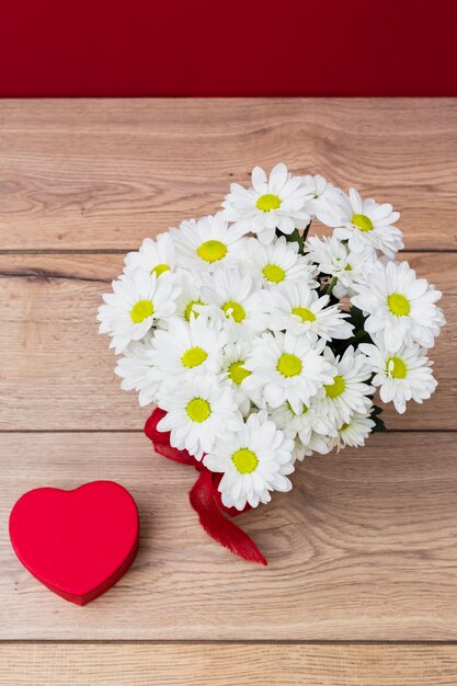 Caja de regalo en forma de corazón con ramo de margaritas.