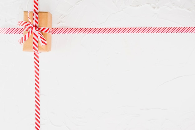 Caja de regalo en funda marrón con cinta rayada.