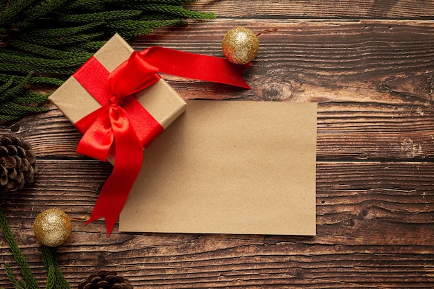 Caja de regalo con lazo de cinta roja sobre fondo de madera