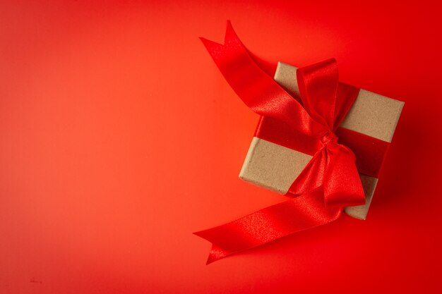 Caja de regalo con lazo de cinta roja sobre fondo rojo.