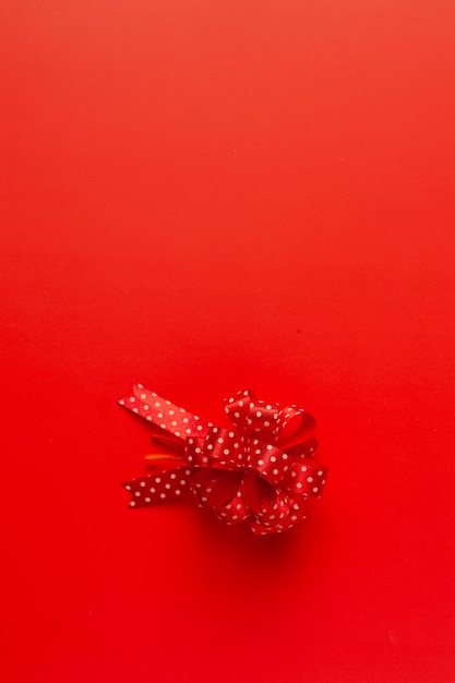Caja de regalo con lazo de cinta roja sobre fondo rojo.