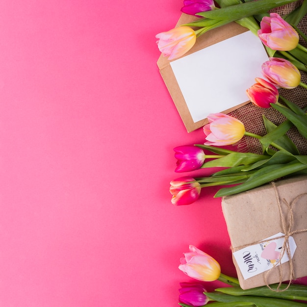 Caja de regalo y letra alrededor de tulipanes.