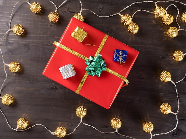 Caja de regalo de Navidad sobre fondo de madera con pequeños regalos y luz de Navidad. Felices vacaciones de invierno.