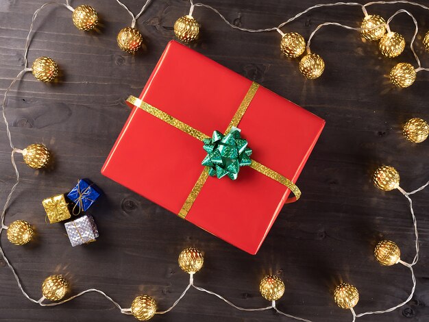 Caja de regalo de Navidad sobre fondo de madera con pequeños regalos y luz de Navidad. Felices vacaciones de invierno.