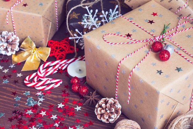 Caja de regalo navideña en una mesa festiva decorada con piñas de caña de caramelo y estrellas de destellos sobre fondo de madera