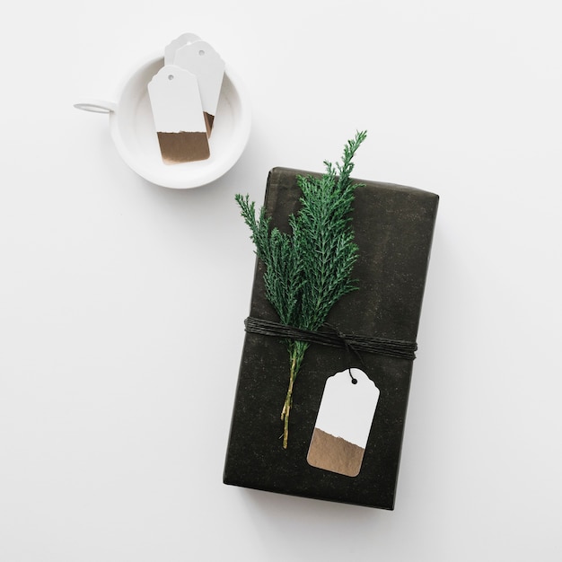 Caja de regalo negra con rama de ciprés en mesa de luz