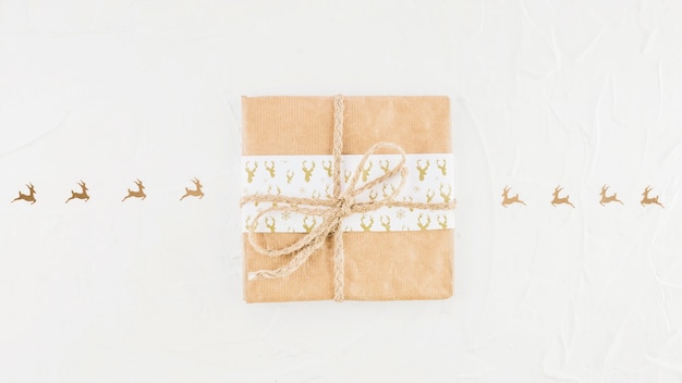 Caja de regalo en papel artesanal cerca de ciervo adorno.