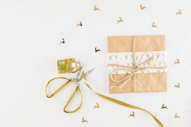 Caja de regalo en papel artesanal cerca de tijeras y cinta.