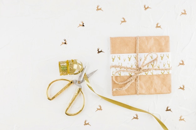 Caja de regalo en papel artesanal cerca de tijeras y cinta.