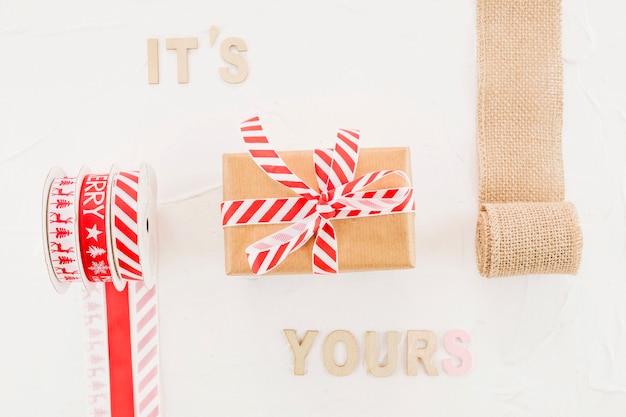 Caja de regalo en papel artesanal con cinta cerca de rodillo elástico e inscripción