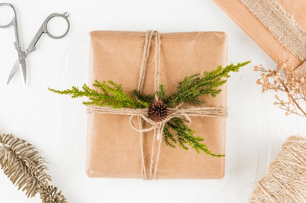 Caja de regalo en papel artesanal con ramita de coníferas.