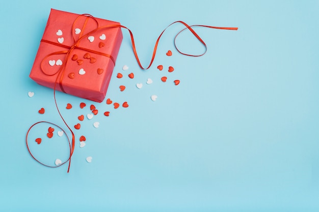 Caja de regalo con pequeños corazones en mesa azul.