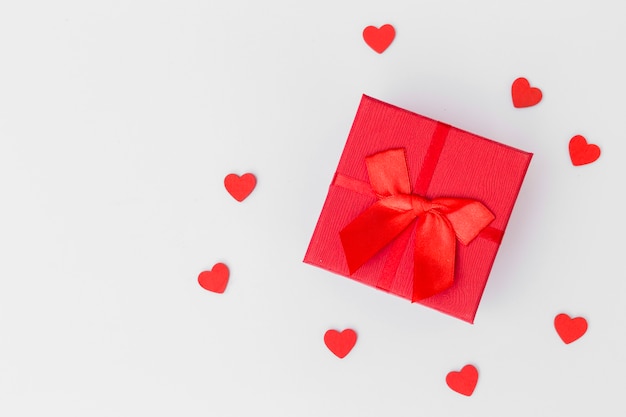 Caja de regalo con pequeños corazones en mesa blanca.