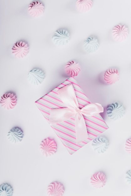 Caja de regalo a rayas atada con cinta y decorada crema batida sobre fondo blanco