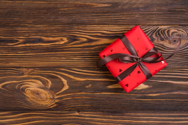 Caja de regalo roja con lazo marrón.