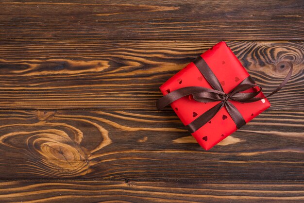Caja de regalo roja con lazo marrón.