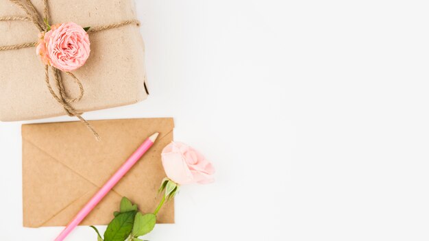Caja de regalo; sobre; lápiz de color y flor color de rosa sobre fondo blanco