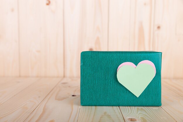 Caja de regalos verde con corazones de papel vista desde enfrente