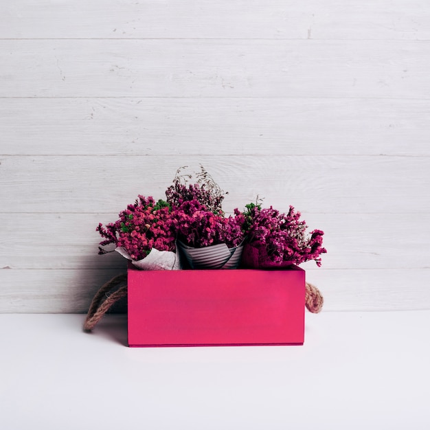 Caja roja con el ramo de flores sobre fondo de madera.