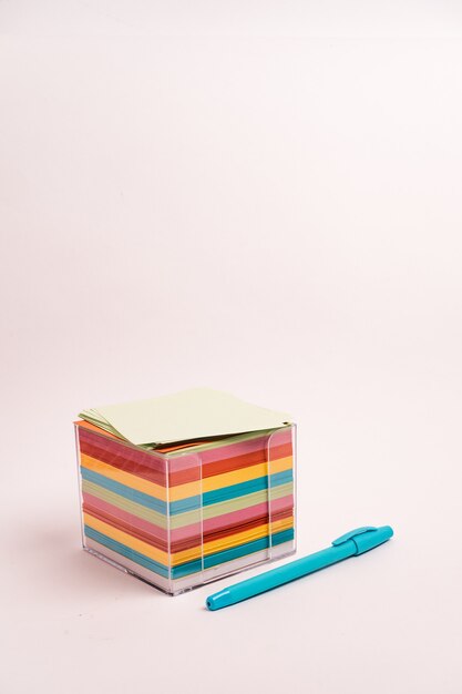 Caja transparente de pegatinas de colores y un bolígrafo azul sobre un blanco