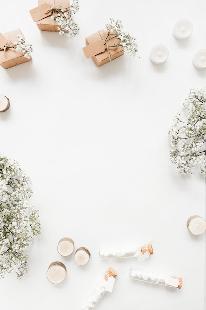 Cajas de regalo; velas; Tubos de ensayo de malvavisco y flores de aliento de bebé sobre fondo blanco