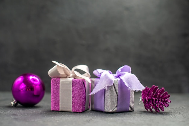 Foto gratuita cajas de regalo de vista superior de color rosa y morado con cintas juguetes de árbol de navidad de color rosa sobre fondo oscuro aislado espacio libre