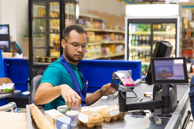 Cajero afroamericano enfocado escaneando productos al momento de pagar