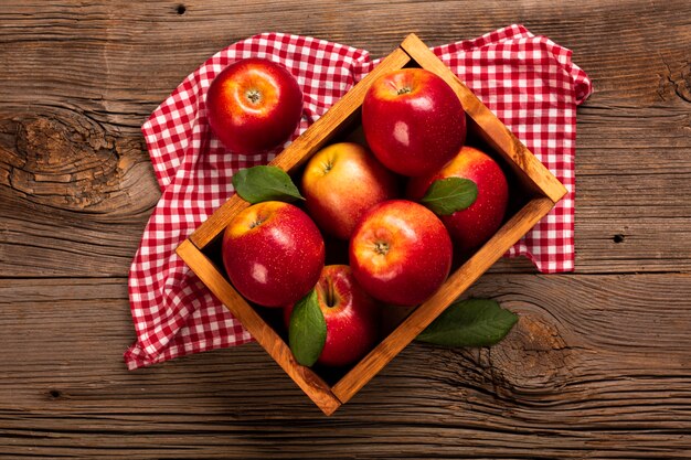 Cajón plano con manzanas maduras sobre tela.