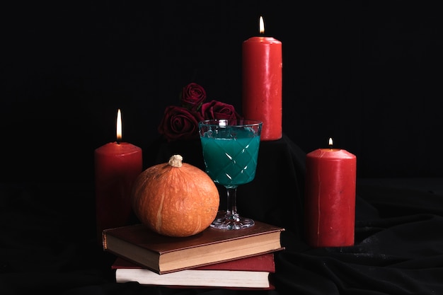 Calabaza con bebida verde y velas.