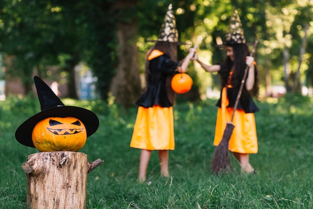 Calabaza de Halloween en el fondo de las niñas en trajes de brujas