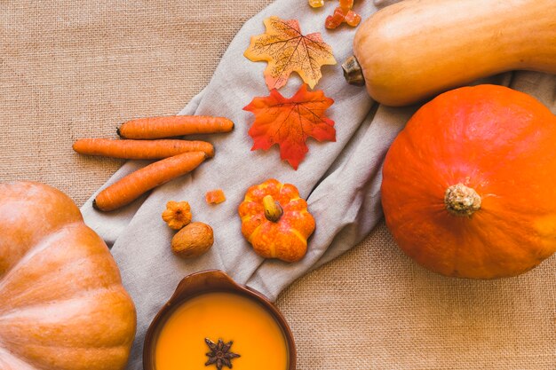 Calabazas y zanahorias cerca de hojas y sopa