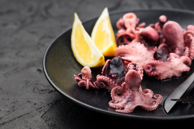 Calamares en plato con cuchillo y rodajas de limón