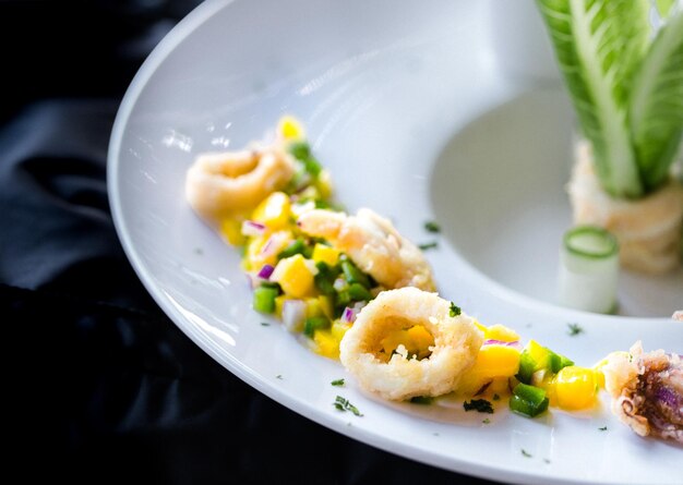 Calamares con salsa de mango con bonita decoración en placa blanca.