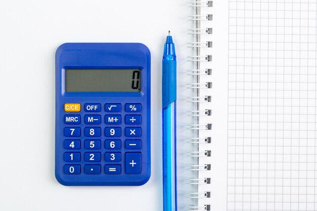 Calculadora azul junto con bolígrafo azul y cuaderno