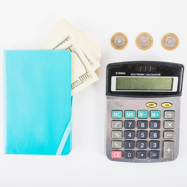 Calculadora con dinero y cuaderno en la mesa