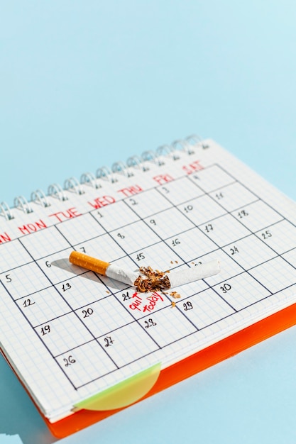 Foto gratuita calendario de alto ángulo con cigarrillo