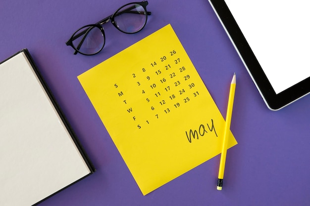 Calendario amarillo plano laico y gafas de lectura