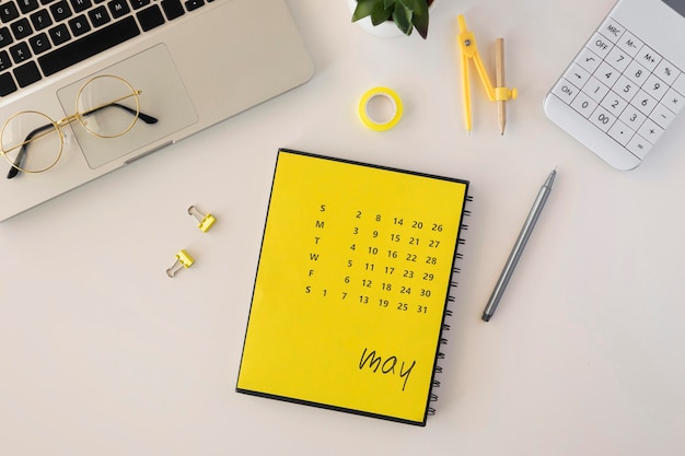 Foto gratuita calendario de escritorio plano con laptop y gafas de lectura