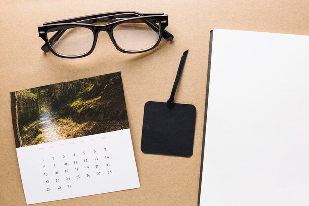 Calendario y gafas cerca del cuaderno