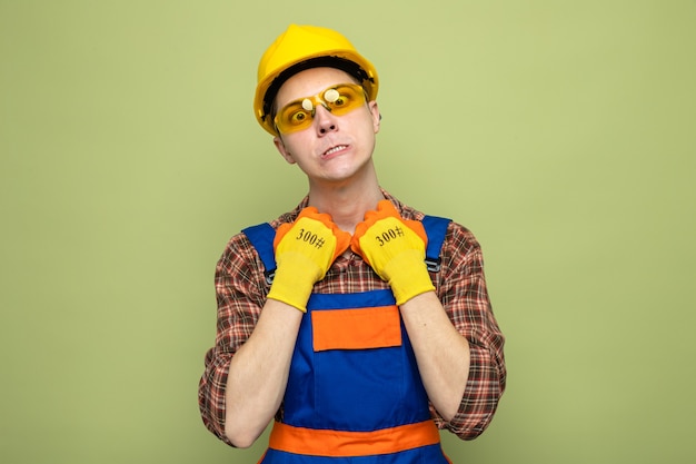 Foto gratuita calentado agarró collar joven constructor masculino con uniforme y guantes con gafas