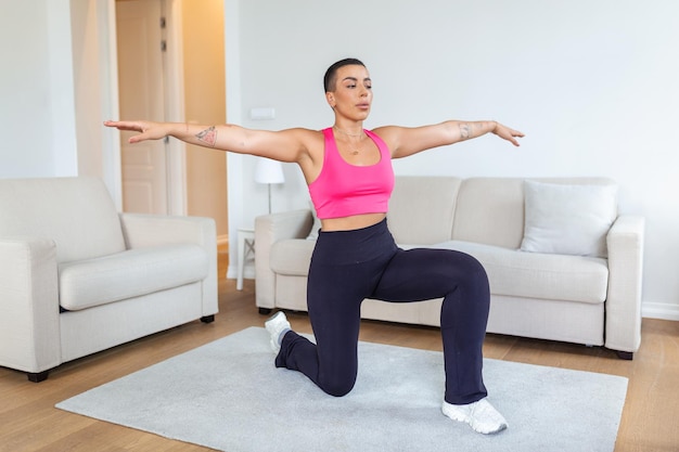 Calentamiento antes del entrenamiento Sonriente mujer negra deportiva entrenando en casa o en el estudio del club de fitness Hermosa mujer estirando las piernas después de los ejercicios en la alfombra