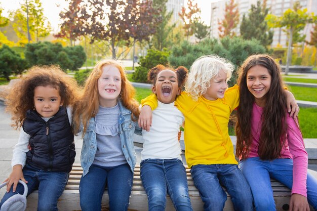 Calentar. Grupo interracial de niños, niñas y niños jugando juntos en el parque en verano.