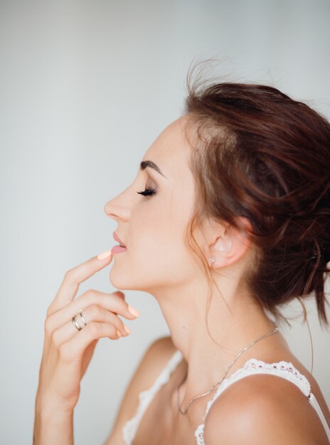 Cálido retrato de la hermosa joven morena tocando sus labios tierna