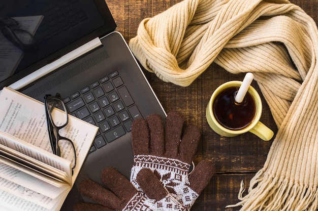 Foto gratuita caliente la ropa y la bebida caliente cerca de la computadora portátil y el libro