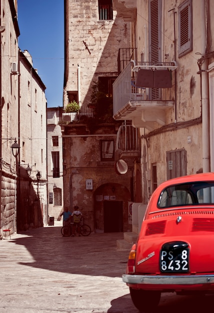 Calle con un coche rojo viejo