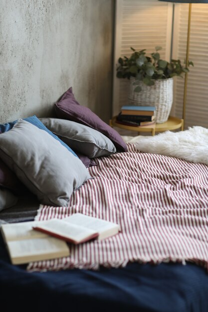 Cama con almohadas y libro abierto.