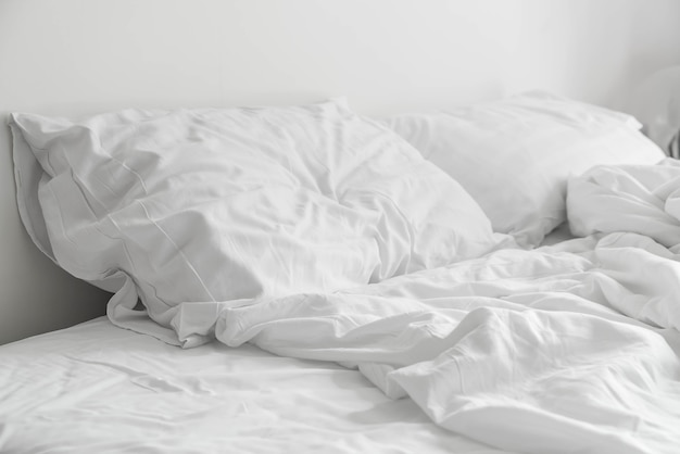 Cama arrugada con decoración de almohada blanco desordenado en el dormitorio