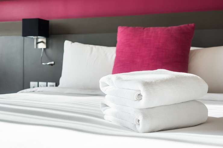 Foto gratuito cama con dos toallas blancas y un cojín
