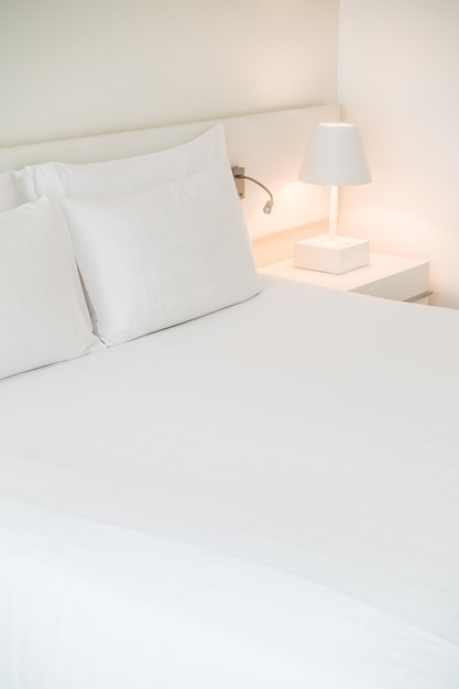 Cama hecha blanca con lamparita de noche