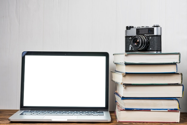 Cámara y libros cerca de la computadora portátil